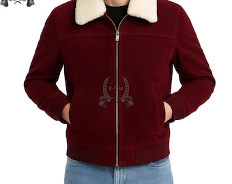 May include: A burgundy bomber jacket with a cream-colored shearling collar. The jacket has a zip-up front, two front pockets, and a ribbed hem and cuffs. The jacket features a logo on the chest.
