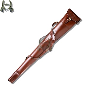 Op de afbeelding: Een bruine leren geweerkoffer met een klepsluiting en een messing gesp. De koffer heeft een schouderriem en een handvat. Het leer heeft een glanzende afwerking. De koffer is ontworpen om een lang wapen te bevatten.