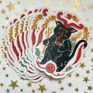 May include: A stack of black cat stickers with red horns, a red bow tie, and a variety of other details. The cat is surrounded by a variety of objects, including a ball of yarn, a mouse, a bird, and a bone.