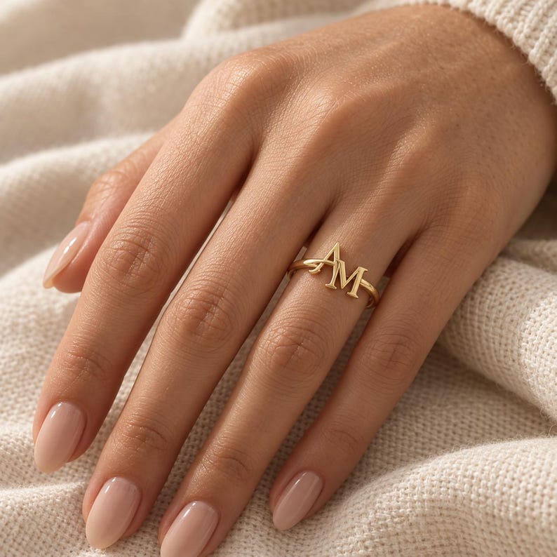 Handcrafted two initial ring in polished gold, 925 sterling silver, and rose gold. Features an elegant interlocking monogram with two custom initials for couples, lovers, or best friends. Dainty personalized letter band worn on woman's finger, displayed on stone tile and velvet ring box. Perfect romantic anniversary gift, promise ring, or birthday gift for her.
