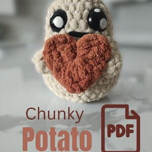 Op de afbeelding: Een handgemaakte, beige gehaakte aardappelknuffel met grote zwarte ogen en een gestikte glimlach, met een getextureerd, roestkleurig hart. De tekst "Chunky Potato PDF" wordt weergegeven in een bijpassende roestkleur.