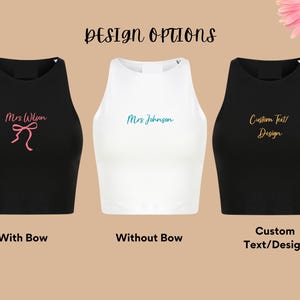 Op de afbeelding: Drie mouwloze crop tops in zwart en wit, met de tekst "DESIGN OPTIONS" bovenaan. De zwarte tops hebben roze tekst en een strikdesign, en gouden tekst. De witte top heeft turquoise tekst. De onderkant van de afbeelding heeft de tekst "With Bow", "Without Bow" en "Custom Text/Design".