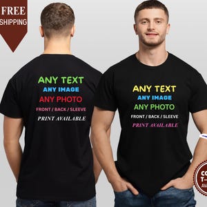 May include: Two people wearing black t-shirts. The front of the shirt has the text "ANY TEXT, ANY IMAGE, ANY PHOTO, FRONT/BACK/SLEEVE, PRINT AVAILABLE" in various colours. The back of the shirt has the same text. A brown banner says "FREE SHIPPING".
