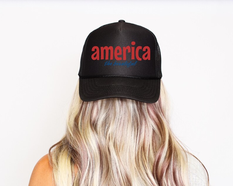 K&ouml;nnte beinhalten: Schwarze Trucker-M&uuml;tze mit dem Wort "America" in roten Buchstaben und "the beautiful" in blauer Schrift. Die M&uuml;tze wird von einer Person mit blondem Haar getragen.