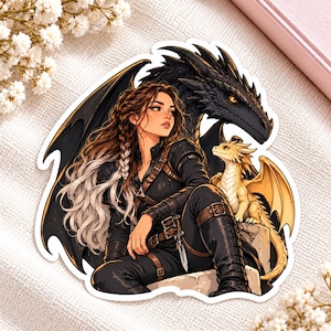 May include: A die-cut sticker featuring a person with long brown and white hair wearing a black outfit with a belt and dagger. A large black dragon with orange eyes looms behind them, while a small yellow dragon sits on a stone block nearby.