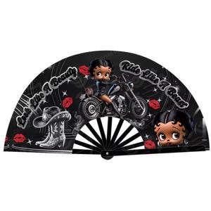 May include: Black folding fan with a cartoon image of a woman riding a motorcycle. The fan has the text "Look Like A Beauty, Ride Like A Beast" on it.
