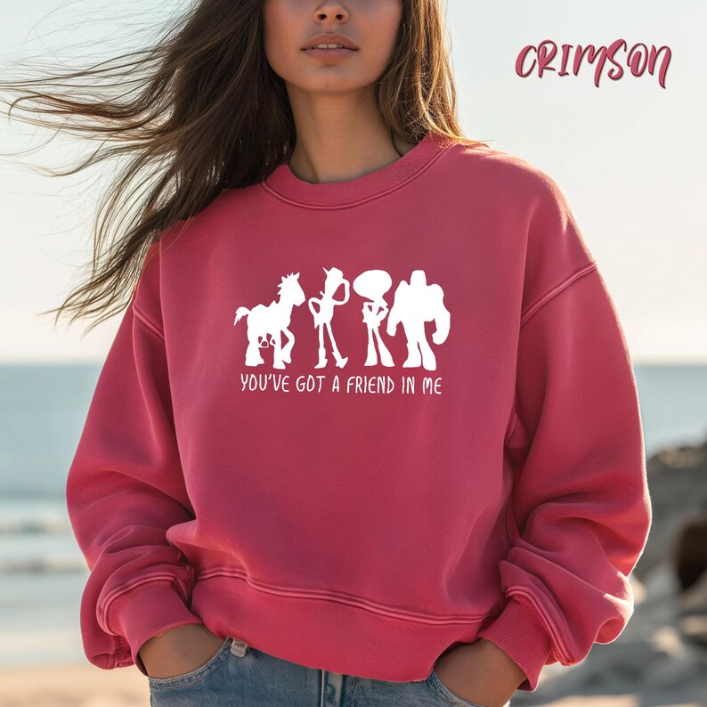 May include: Crimson-colored sweatshirt with a white graphic of three cartoon characters and a horse. The text "YOU'VE GOT A FRIEND IN ME" is below the graphic. The word "CRIMSON" is written in cursive in the upper right corner.