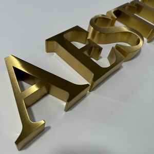 Letras personalizadas en oro cepillado, letreros con logotipos personalizados en metal dorado, letreros con logotipos de empresas en 3D, letreros con letras comerciales, letreros con logotipos en metal cepillado, letreros de pared dorados