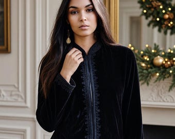 May include: A black velvet jacket featuring a mandarin collar and intricate tonal embroidery along the front placket and sleeve cuffs. The long-sleeved garment has a straight hemline and is worn over a white shirt and black trousers.