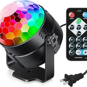 May include: A black LED disco ball light with a colorful, geometric pattern on the dome. Includes a remote control with various function buttons. The light has a power cord with a two-prong plug.