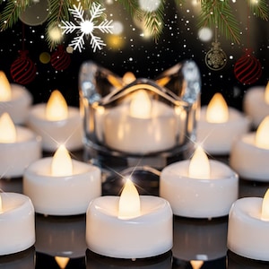 May include: White LED tea light candles with a flickering flame effect. The candles are arranged on a reflective surface, with a clear glass candle holder in the background. Festive holiday decor.