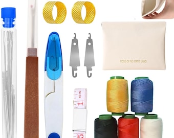 Puede incluir: Un kit de costura con varias herramientas, que incluye agujas en un tubo, un abridor de costuras, un cortahilos azul y blanco, dos dedales dorados, dos enhebradores plateados, una bolsa blanca con texto, carretes de hilo amarillo, azul, negro, rojo y blanco, y una cinta métrica.