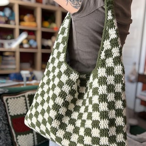 Peut inclure: Un sac fourre-tout crochet&eacute; &agrave; la main avec un motif de damier vert et blanc. Le sac a une large bandouli&egrave;re et un int&eacute;rieur spacieux. Le sac est fait de fil doux et est parfait pour transporter des courses, des livres ou d'autres articles. Un accessoire &eacute;l&eacute;gant et pratique.