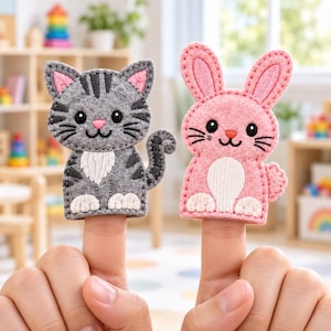 Könnte beinhalten: Zwei Fingerpuppen aus Filz, bestehend aus einer grauen getigerten Katze mit schwarzen Streifen und einem rosa Hasen mit langen Ohren. Beide Puppen haben gestickte Gesichtsmerkmale, darunter schwarze Augen, rosa Nasen und weiße Bauchflecken.
