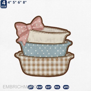 Może przedstawiać: Haftowany wzór przedstawiający trzy ułożone w stos, dekoracyjne miski z brązowym obrysem. Górna miska jest kremowa, środkowa miska jest jasnoniebieska z białymi kropkami, a dolna miska ma brązowo-biały wzór w kratę. Różowa kokarda z białymi kropkami spoczywa na miskach.