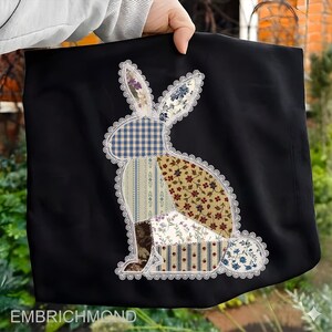 May include: Black fabric tote bag featuring a patchwork bunny design. The bunny is composed of various patterned fabrics in blue, red, and cream, outlined with white lace. The text "EMBRICHMOND" is at the bottom.