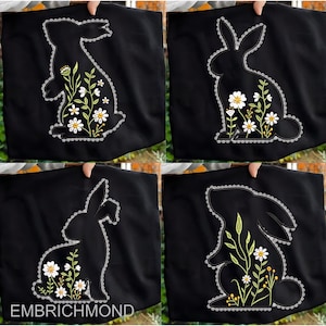 May include: Black tote bags with a bunny silhouette design. Each bag features a different floral arrangement in white, yellow, and green. The bunny outline is bordered with a white scalloped trim. The text "EMBRICHMOND" is at the bottom of one bag.