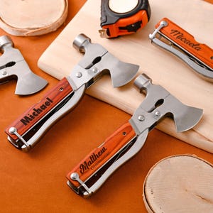 May include: A collection of personalized multi-tools with wooden handles and stainless steel components. Each tool features a hammer, axe, and pliers, with names like "Michael" and "Matthew" engraved on the handles. A measuring tape and wooden coasters are also present.