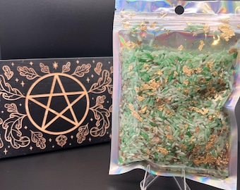 May include: A clear plastic bag filled with green and white rice, with gold flakes sprinkled throughout. The bag is standing on a clear plastic stand.