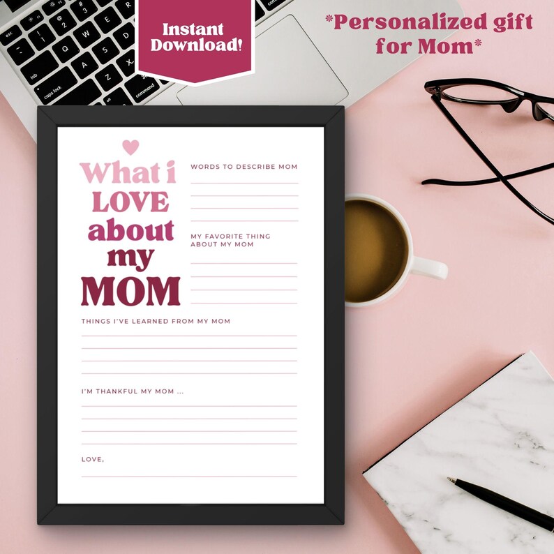 K&ouml;nnte beinhalten: Ein gerahmter Druck mit dem Text "What i LOVE about my MOM" in Rosa und Wei&szlig;. Der Druck enth&auml;lt Ausf&uuml;llfelder f&uuml;r W&ouml;rter zur Beschreibung von Mama, Lieblingsdinge und gelernte Dinge. Ein Laptop, eine Kaffeetasse und eine Brille sind im Hintergrund.