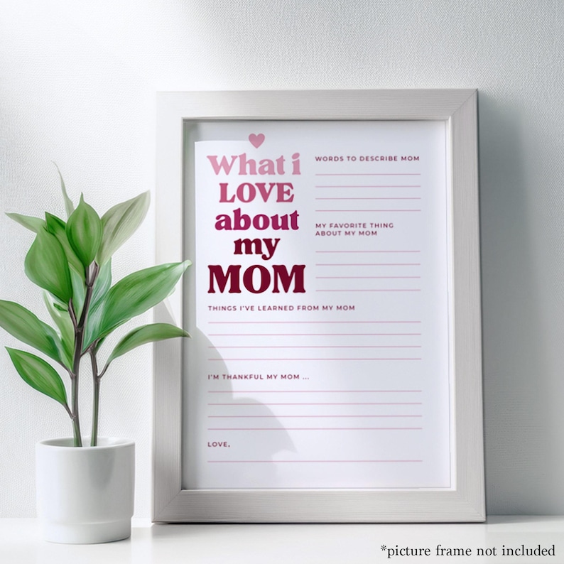K&ouml;nnte beinhalten: Ein gerahmter Druck mit dem Text "What I LOVE about my MOM" in Rosa und Burgunder. Der Druck enth&auml;lt Aufforderungen, Mama, Lieblingsdinge und Gelernte zu beschreiben. Links ist eine kleine Topfpflanze.