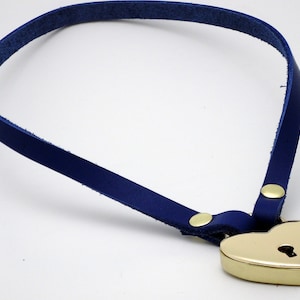 May include: A blue leather choker necklace with a gold heart-shaped padlock. The padlock has a keyhole.