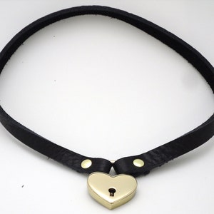 May include: A black leather choker with a gold heart-shaped padlock.