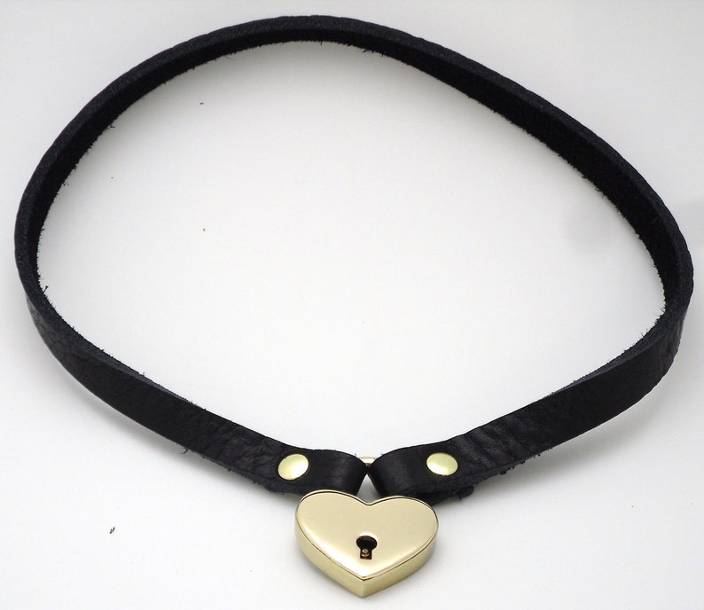 May include: A black leather choker with a gold heart-shaped padlock.