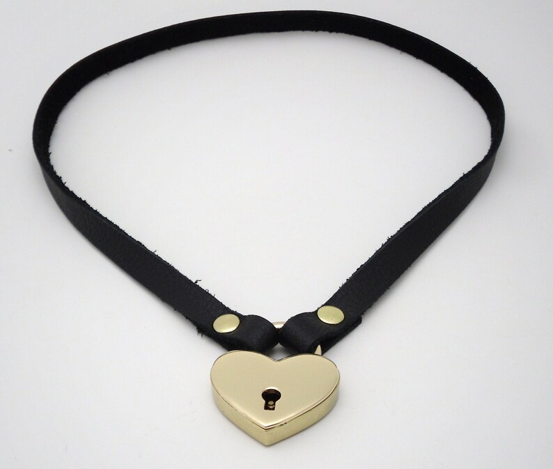 May include: A black leather choker with a gold heart-shaped padlock.