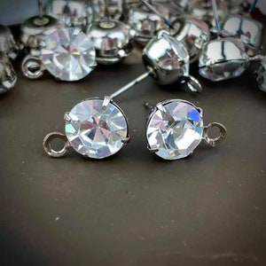May include: A pair of silver earring findings with clear crystal rhinestones. The findings have a loop on the side for attaching to jewellery.