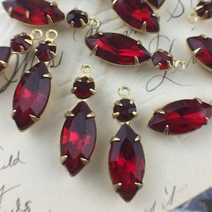 May include: A group of red glass teardrop-shaped pendants with gold-tone metal settings. The pendants are strung on a gold-tone chain.