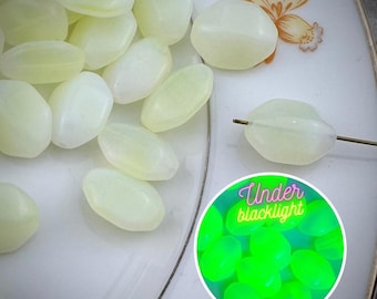 Könnte beinhalten: Nahaufnahme einer Ansammlung ovaler, hellgrüner Glasperlen. Die Perlen sind auf einem weißen Teller mit Blumenmuster angeordnet. Eine einzelne Perle ist auf einem Draht dargestellt, und ein separates Bild zeigt die Perlen, die unter Schwarzlicht grün leuchten. "Under blacklight" ist in rosa und grüner Schrift geschrieben.