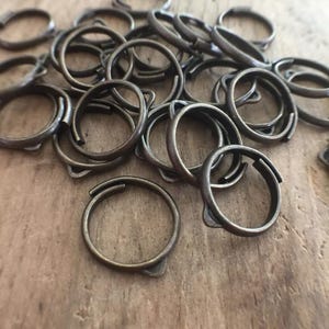May include: A pile of antique brass rings, each with a unique shape and design. The rings are arranged in a random pattern, creating a visually appealing and textured image.