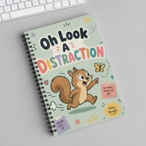 Könnte beinhalten: Ein spiralgebundenes Notizbuch mit hellgrünem Einband mit dem Text "Oh Look A DISTRACTION". Ein Cartoon-Eichhörnchen zeigt auf einen Schmetterling. Zusätzlicher Text enthält "so many things to do!" und "shiny things!"