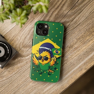 Può includere: Una cover per smartphone verde con un uccellino giallo dei cartoni animati che indossa occhiali da sole neri e una maglia verde. L'uccellino tiene una piccola bandiera brasiliana davanti a un grande disegno circolare della bandiera del Brasile.
