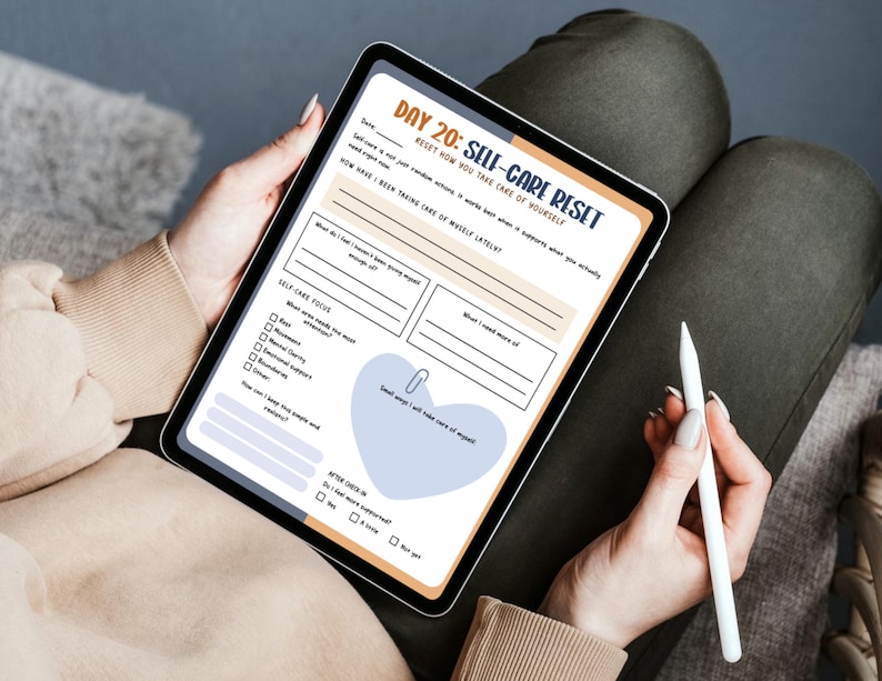 Op de afbeelding: Een digitale tablet met een pagina uit een zelfzorgdagboek met de titel "Dag 20: Self-Care Reset". De pagina bevat prompts, selectievakjes en een hartvormige afbeelding. Een stylus wordt in de buurt gehouden.