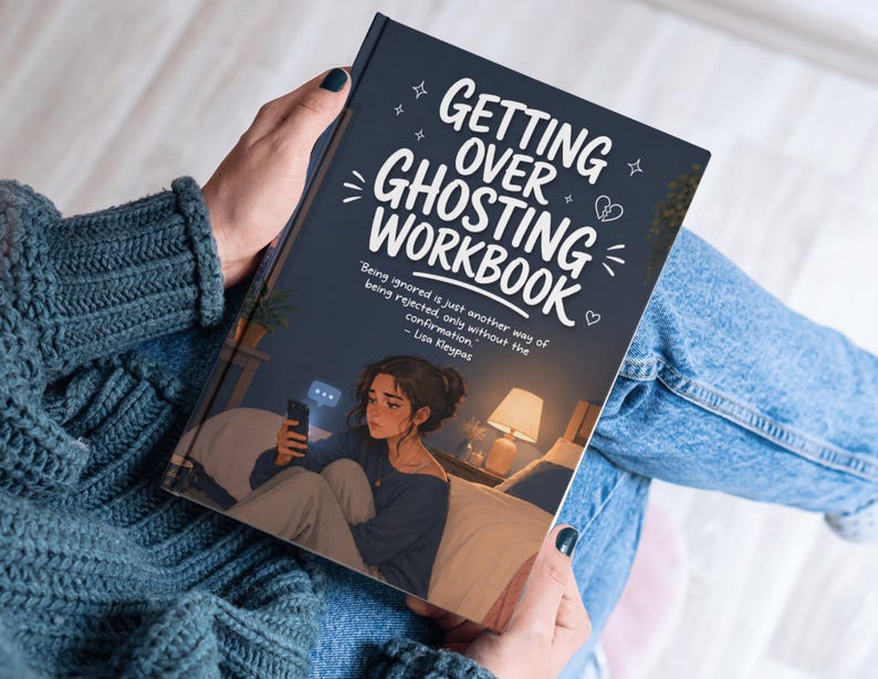 Puede incluir: Un libro titulado "Getting Over Ghosting Workbook" sostenido por una persona. La portada es azul oscuro con texto blanco y una ilustraci&oacute;n de una persona en una cama mirando un tel&eacute;fono. La persona lleva un su&eacute;ter azul y vaqueros.