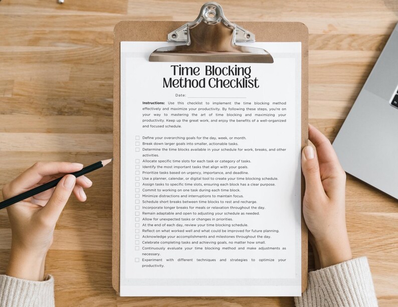 May include: A clipboard with a checklist titled "Time Blocking Method Checklist" is held by two hands. A pencil rests on the paper. The checklist includes instructions and steps for time management. A laptop is partially visible in the background.