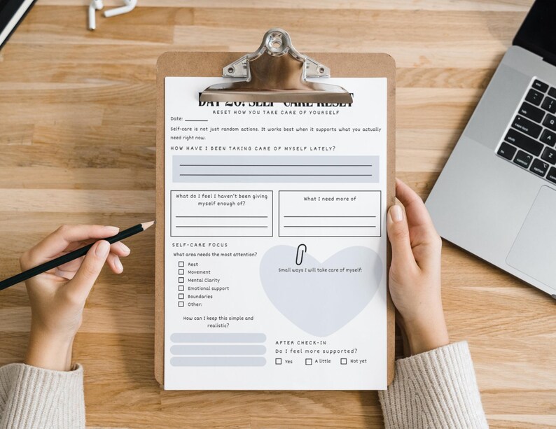 May include: A clipboard with a self-care reset worksheet. The worksheet includes sections for reflection, such as 'How have I been taking care of myself lately?' and 'Self-Care Focus'. A pencil and a laptop are also visible.