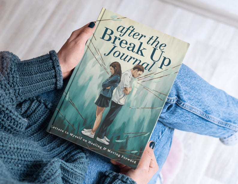 May include: A journal titled "After the Break Up Journal" is held in a person's hands. The cover art depicts a couple standing back-to-back with a teal and white background. The text "Letters to Myself on Healing & Moving Forward" is at the bottom.