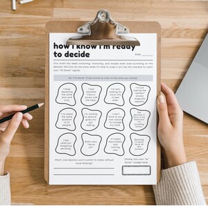 May include: A clipboard with a printed checklist titled "how I know I'm ready to decide" is held by a person. The checklist includes prompts to help with decision-making. A laptop and pencil are also visible.