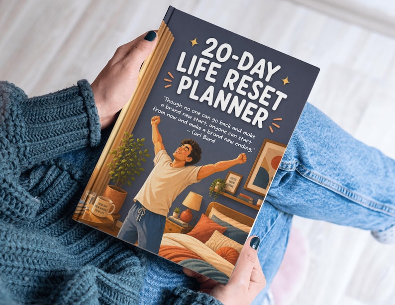 Op de afbeelding: Een persoon die een 20-Day Life Reset Planner vasthoudt. De omslag toont een cartoonillustratie van een persoon met opgeheven armen in een slaapkamer. De titel van de planner is in het wit, met een citaat van Carl Bard.