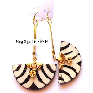 May include: A pair of handmade earrings with a zebra stripe design. The earrings feature a half-circle shape with black and white stripes, gold wire accents, and gold-colored ear hooks. The text "Buy 6 get 6 FREE!!" is visible.