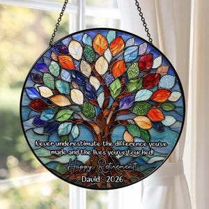Può includere: Un'opera d'arte rotonda per vetrate con un design ad albero colorato. L'albero ha un tronco e rami marroni con foglie multicolori. Il testo recita: "Never underestimate the difference you've made and the lives you've touched! Happy Retirement! David - 2026."