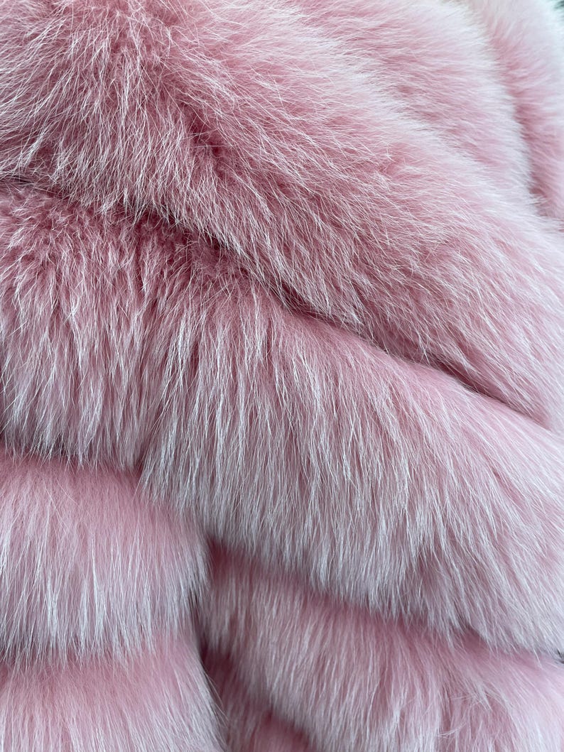 May include: Close-up of a luxurious pink fur texture. The fur appears soft and fluffy, with long, flowing strands in varying shades of pink and white. The image highlights the texture and depth of the fur.