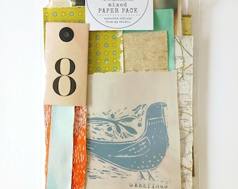 May include: A mixed paper pack with assorted offcuts from Paper Squirrel Store. The pack includes various paper pieces with different textures, colors, and patterns, including a paper with a blue bird illustration and the word "GREETINGS".