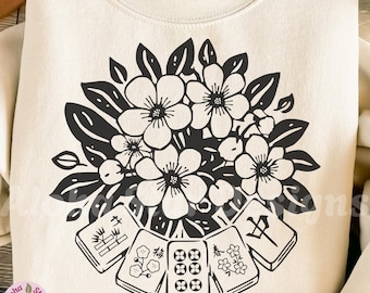 May include: Cream-colored sweatshirt featuring a black floral design and Mahjong tiles. The floral design is a bouquet of flowers with detailed petals and leaves. The Mahjong tiles are arranged below the flowers. The text "Aloha Star Designs" and "alohastardesigns.etsy.com" are also visible.
