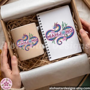 May include: A beige ceramic mug and a spiral-bound notebook with a colorful dragon design and the word "MAHJONG". The design includes bamboo stalks and pink flowers. The items are in a cardboard box with paper filler.