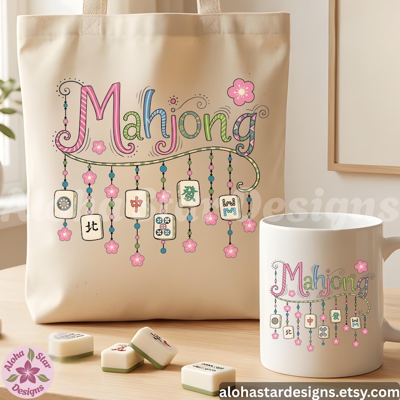 May include: A beige tote bag and white mug with the word "Mahjong" in pink, blue, and green script. The design includes hanging tiles and pink flowers. Several Mahjong tiles are on the table.