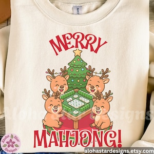 May include: Cream-colored sweatshirt with a festive design. The graphic features four reindeer playing mahjong around a table, a Christmas tree, and the words "MERRY MAHONG!" in red.